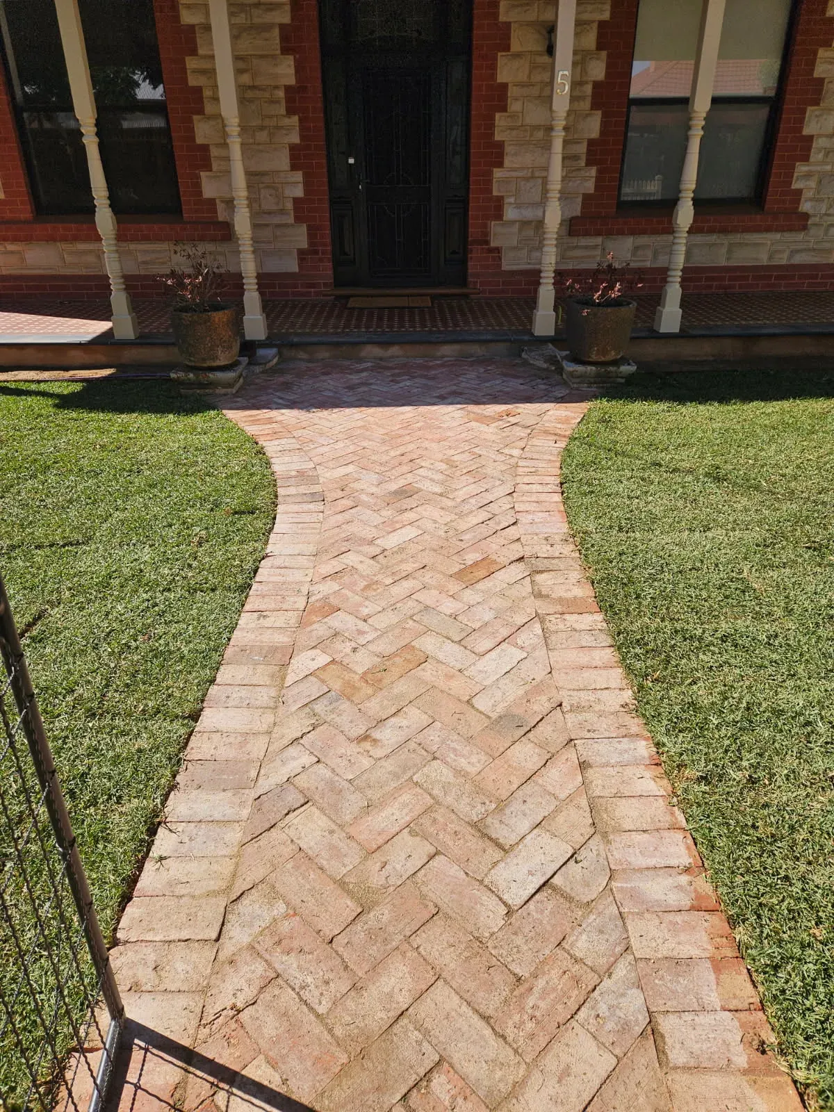 Herringbone brick-paved garden path through a lawn to a front door