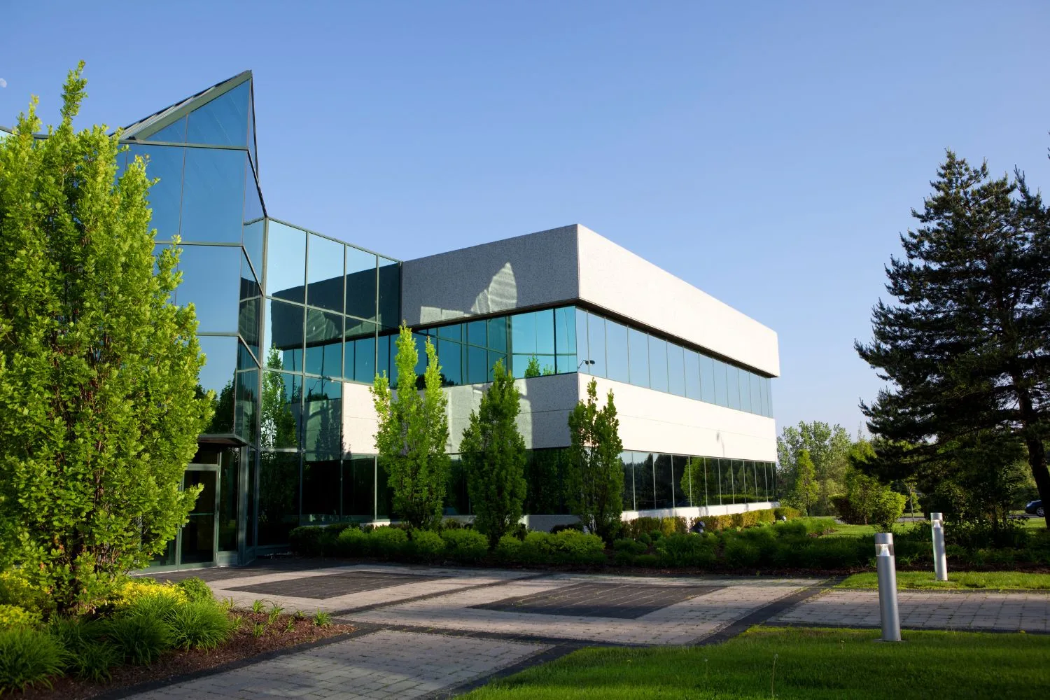 Glass office building with clipped hedges, lawn and feature trees