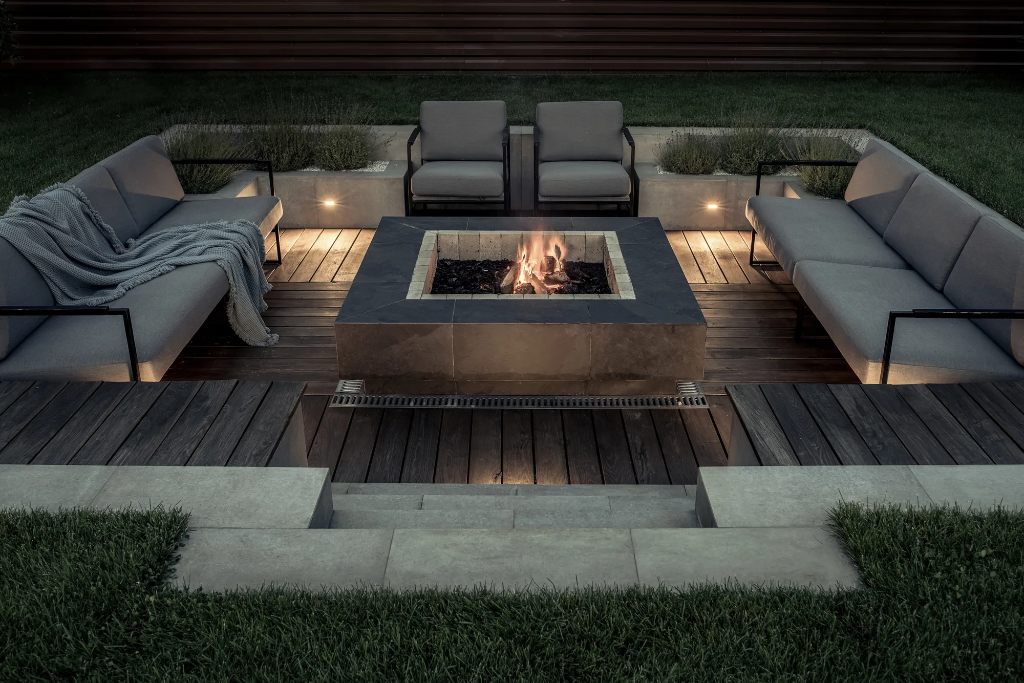 Timber deck lounge with outdoor sofas around a square fire pit