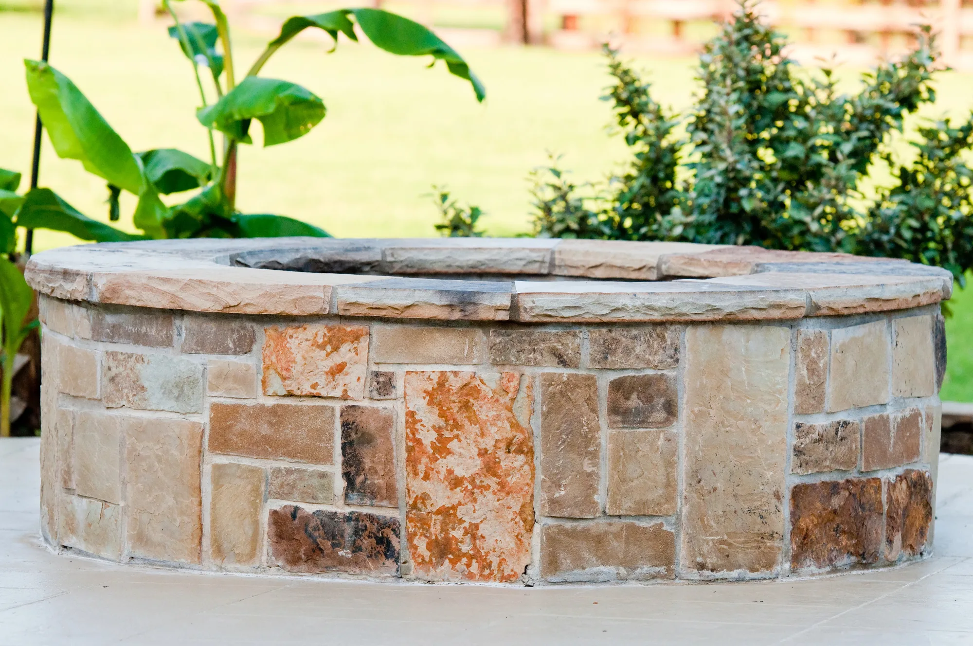 Round natural stone wall fire pit set into a garden
