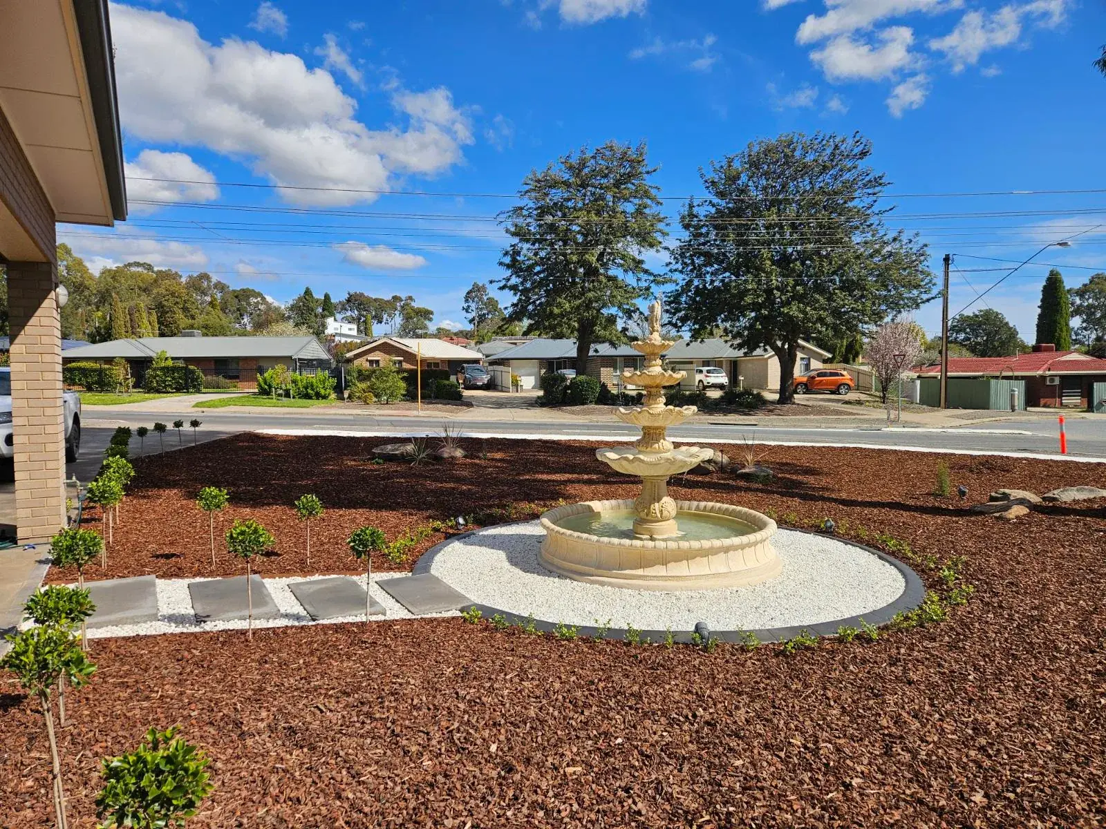 Tiered fountain feature in a mulched garden with stepping pavers