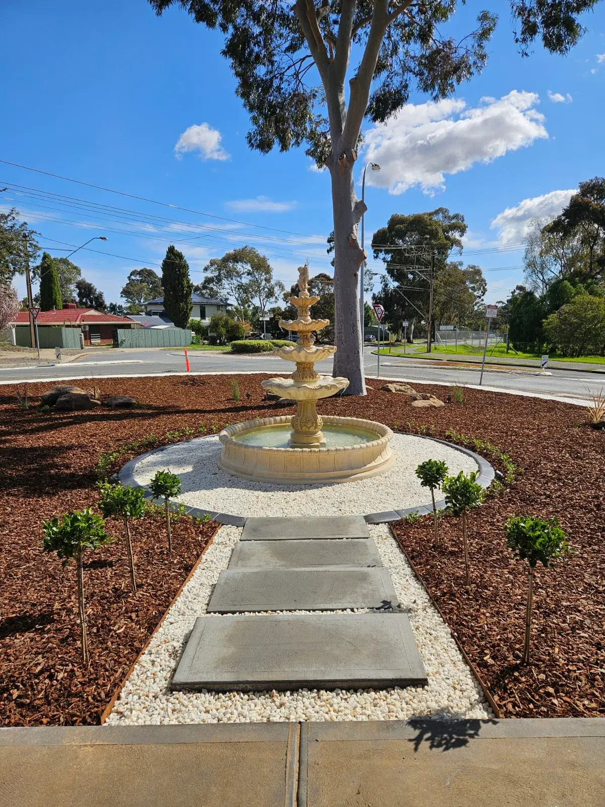 Garden fountain with a stepping-stone path through mulch