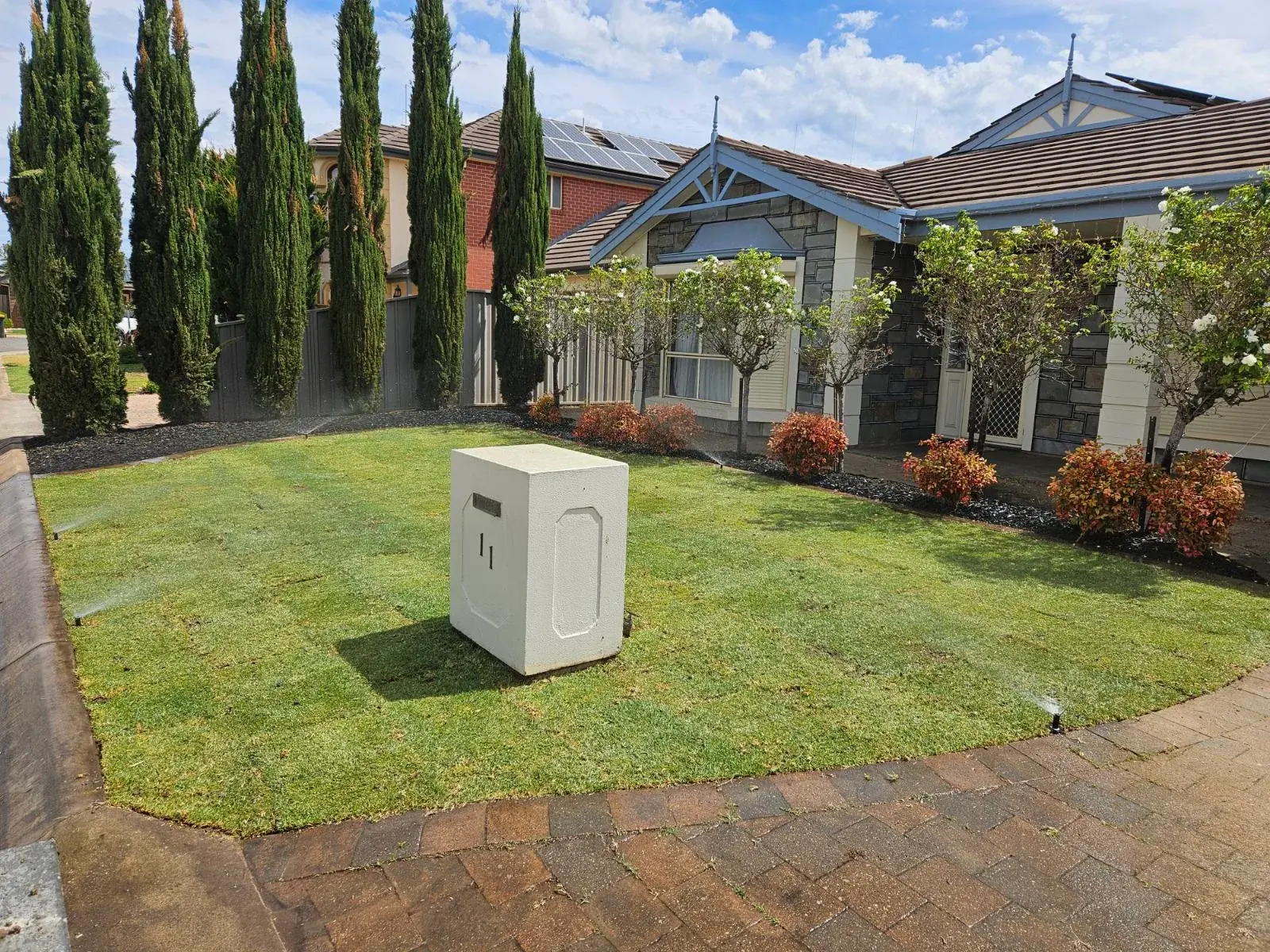 Renovated front garden with new lawn, cypress row and flowering garden beds