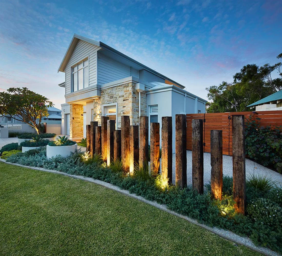 Sloping front garden with timber post feature wall, lighting and layered planting