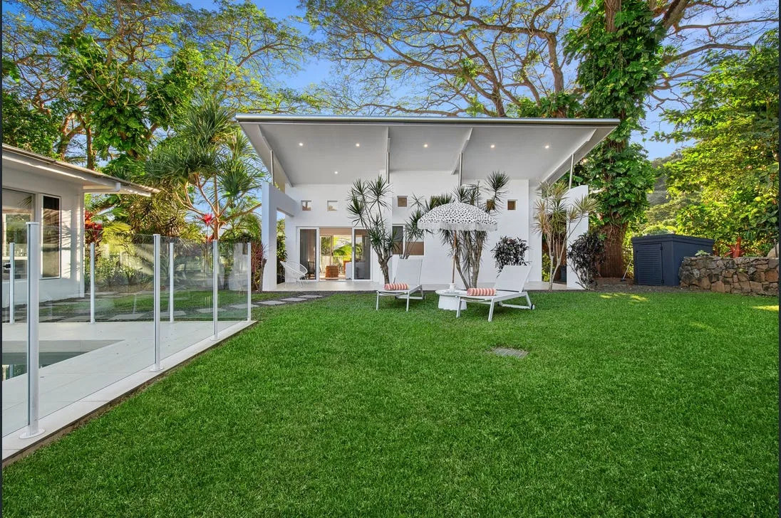 Backyard lawn and pool fencing in front of a white pavilion