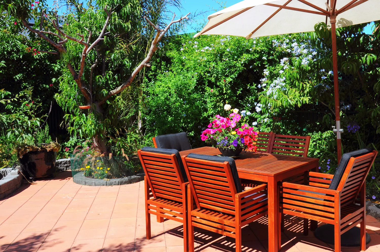 Paved courtyard with a timber outdoor dining setting under an umbrella