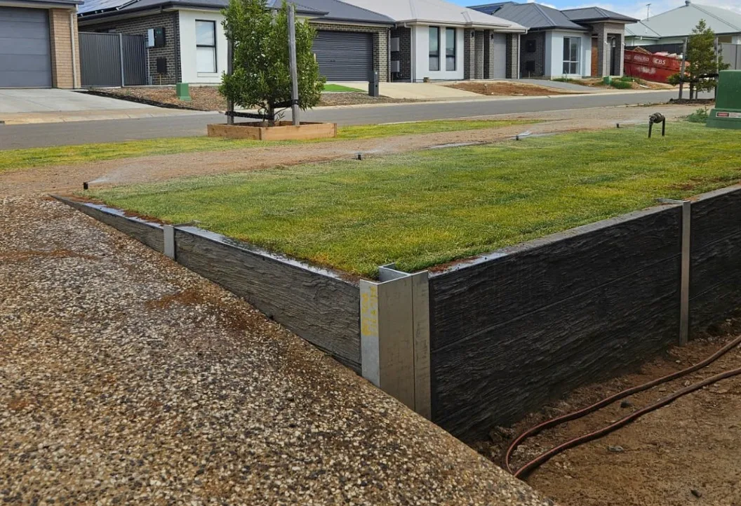 Concrete sleeper retaining wall holding a raised bed of new turf