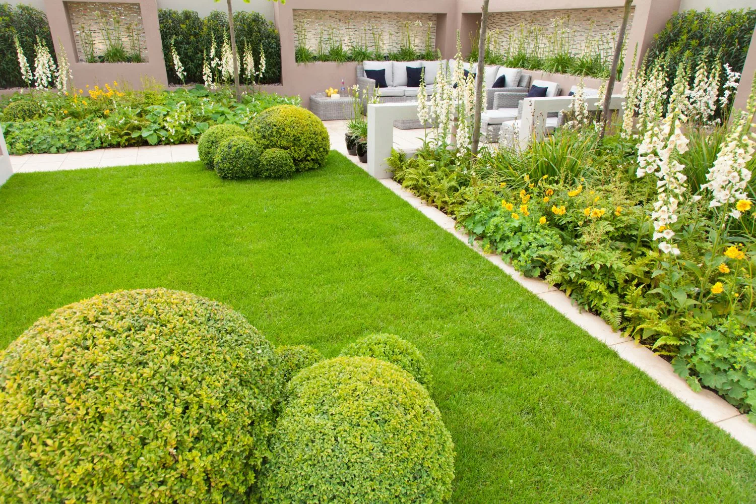 Formal garden with clipped buxus balls, lawn and an outdoor lounge