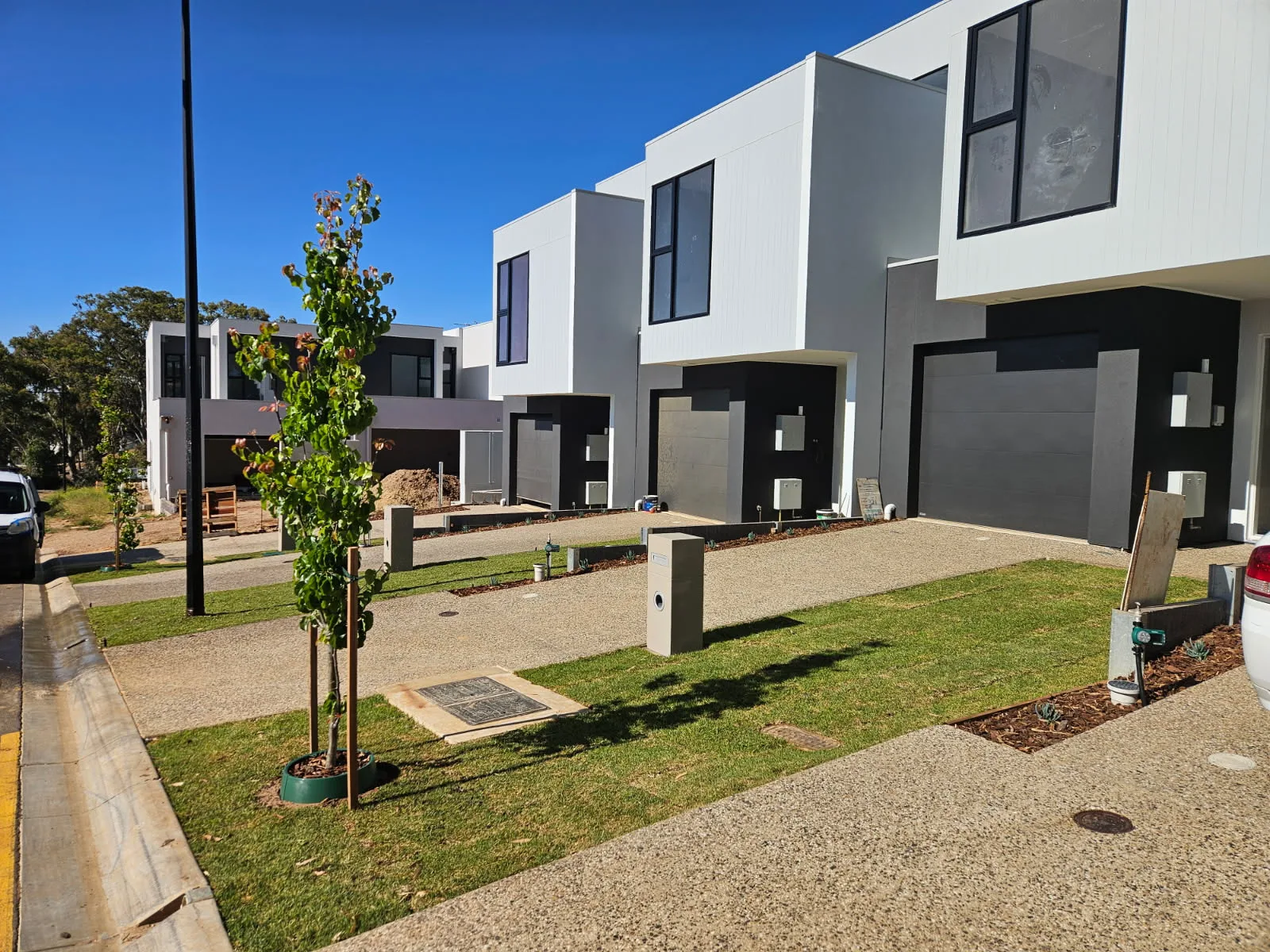 Townhouse frontage with new lawn, garden beds and young trees